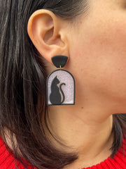 Polymer clay earrings design of black cat seating in a window watching snow fall 